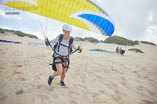 Female paraglider with parachute running  taking off on beach
