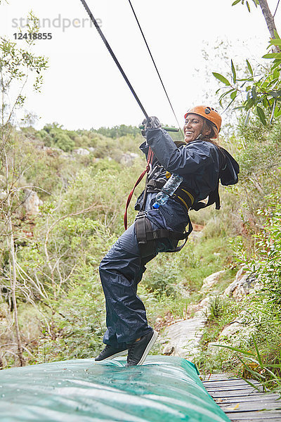 Happy woman zip lining in woods