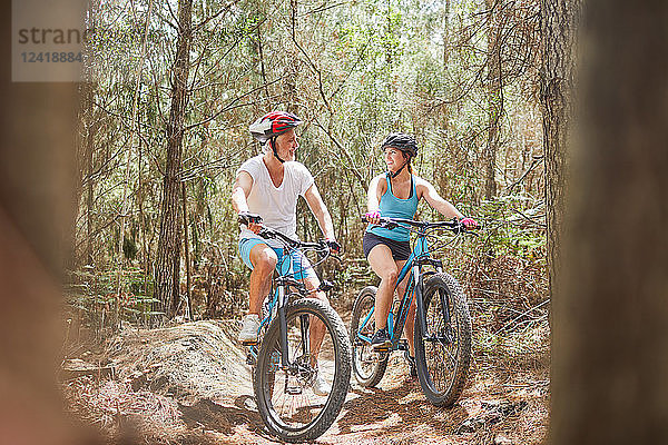 Father and daughter mountain biking on trail in woods