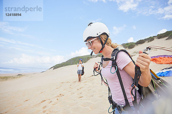 Smiling female paraglider with equipment on beach