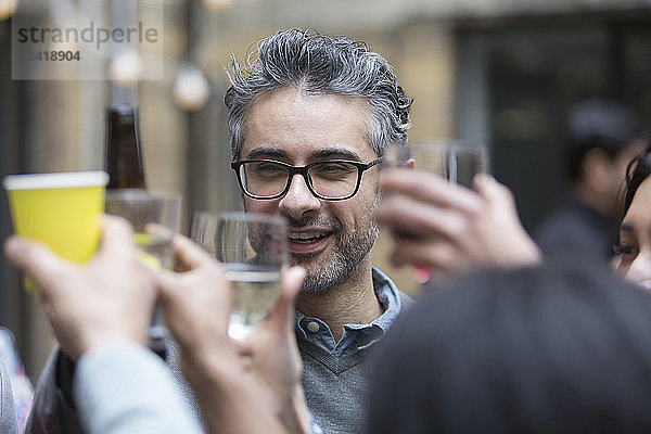 Happy man toasting drinks with friends at party