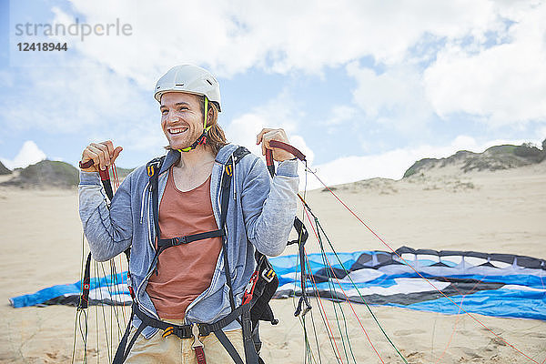 Smiling  confident paraglider with parachute on beach