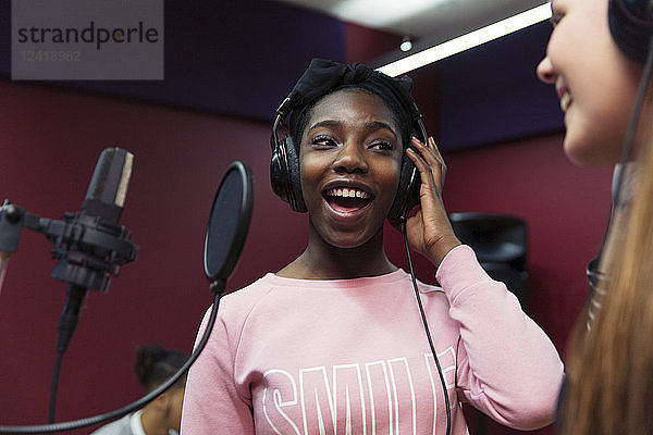 Teenage girl musicians recording music  singing in sound booth