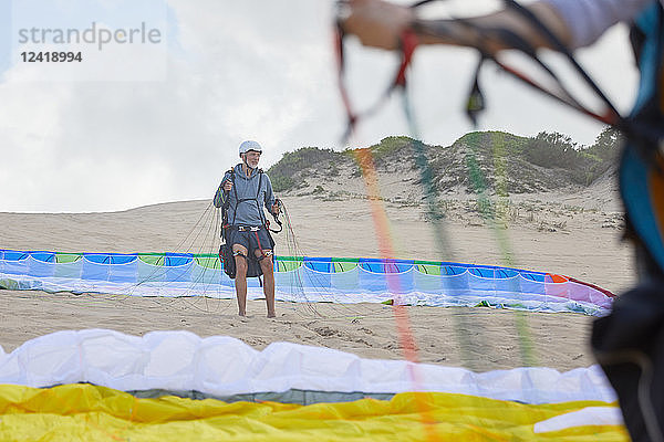 Male paraglider with parachute on beach