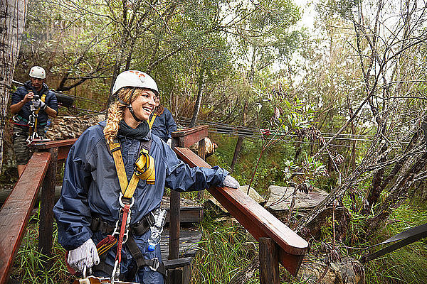 Smiling woman preparing to zip line in woods