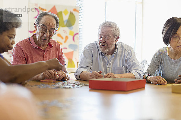Senior friends playing games at table in community center