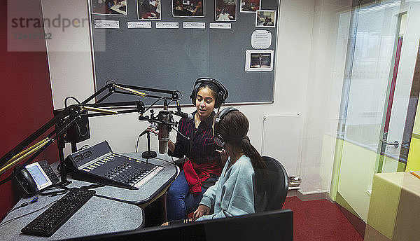 Teenage girl musicians recording music  singing in sound booth