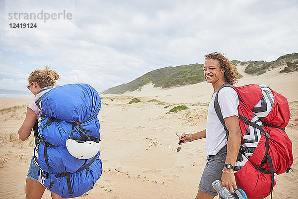 Portrait happy male paraglider with parachute backpack on beach