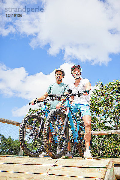 Father and son mountain biking at obstacle course