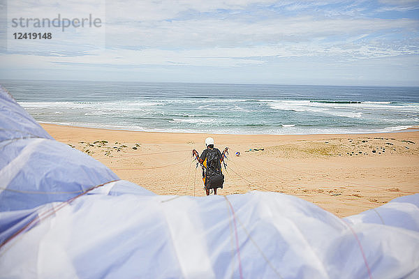 Paraglider with parachute on ocean beach