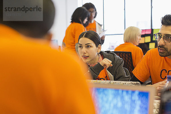 Hackers at laptops coding for charity at hackathon