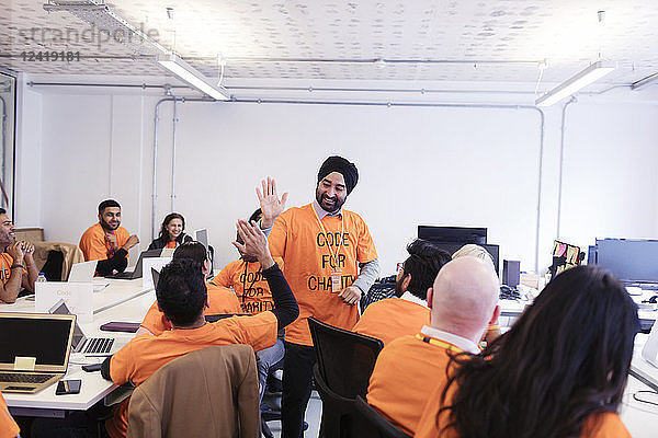 Hackers celebrating  high-fiving and coding for charity at hackathon