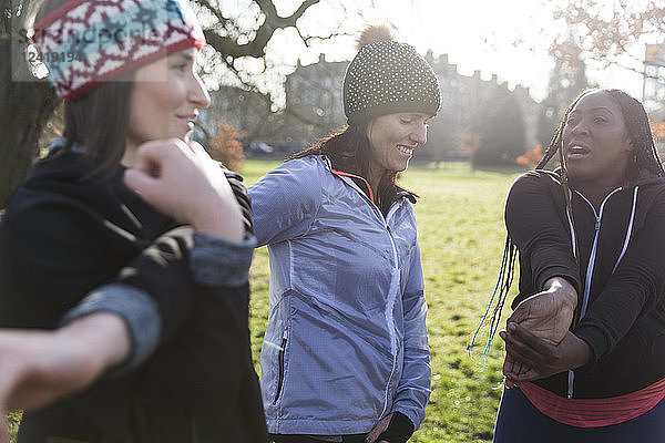 Female runners stretching in sunny park