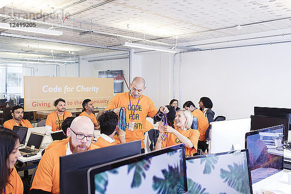 Hackers with lanyards coding for charity at hackathon