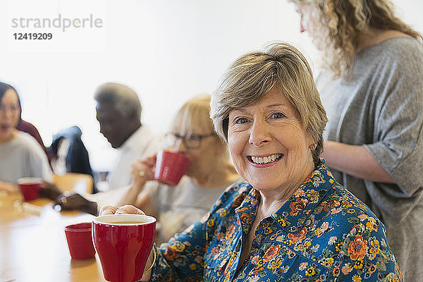 Portrait smiling  confident senior woman drinking tea with friends in community center
