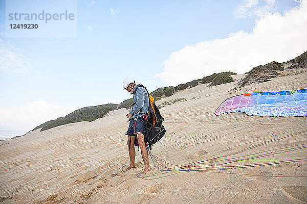Male paraglider preparing equipment on beach