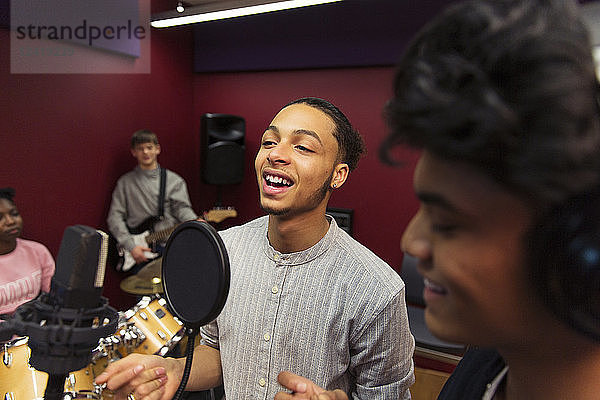 Teenage musicians recording music  singing in sound booth