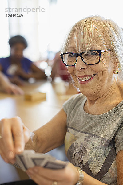 Portrait happy senior woman playing cards in community center