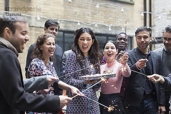 Friends celebrating with woman holding birthday cake