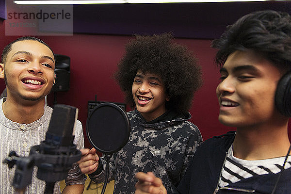 Teenage musicians recording music  singing in sound booth