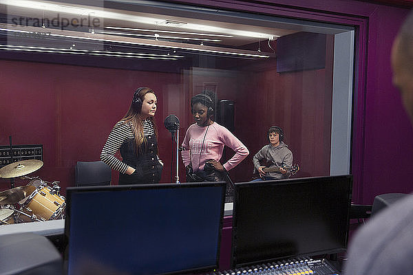Teenage musicians recording music  singing in sound booth