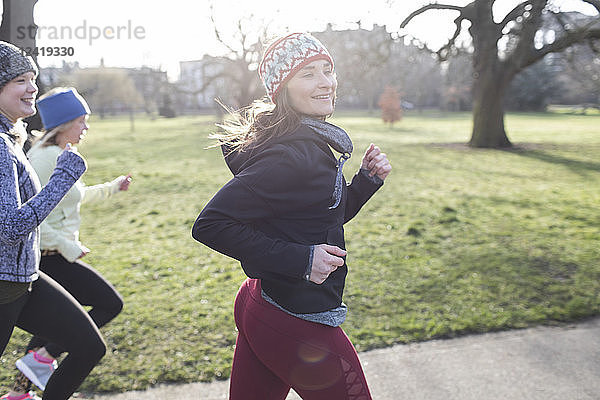 Confident female runner running in sunny park