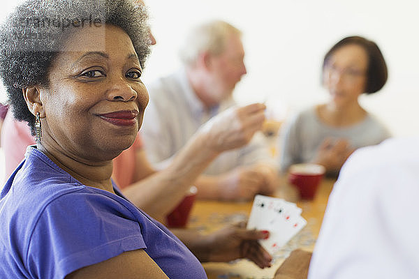 Portrait confident senior woman playing cards with friends in community center