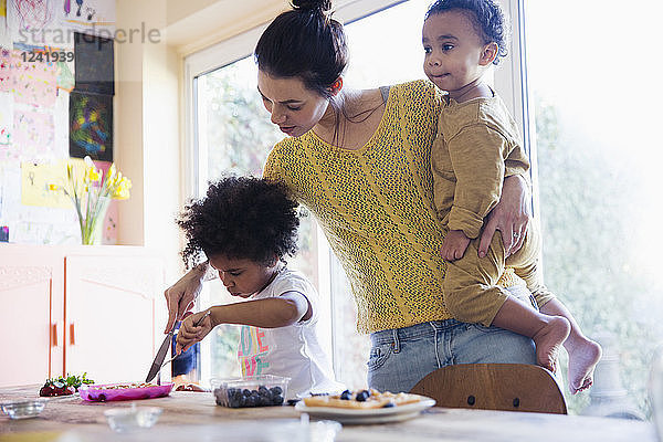 Mutter hilft ihrer kleinen Tochter beim Schneiden von Frühstückswaffeln
