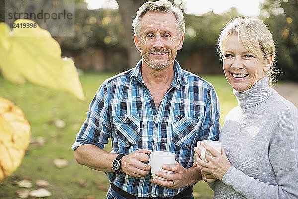 Portrait lächelndes  selbstbewusstes reifes Paar beim Kaffeetrinken im Herbstgarten