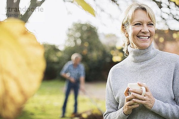 Porträt lächelnd  glücklich reife Frau trinken Kaffee im Herbst Hof