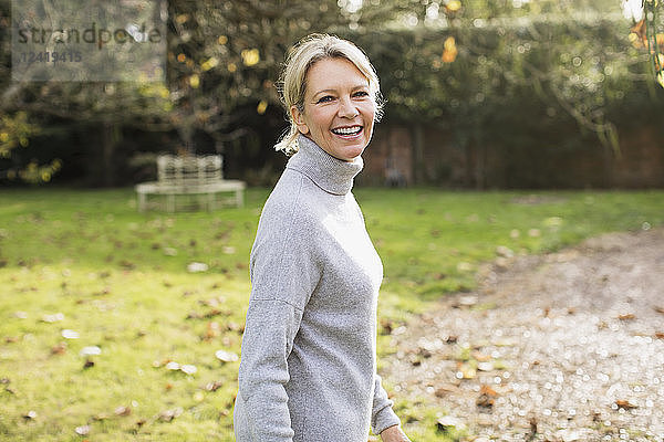 Porträt lächelnd  zuversichtlich reife Frau in sonnigen Herbst Hinterhof