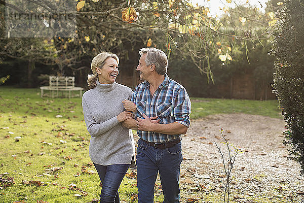 Glücklich  sorglos reifen Paar zu Fuß Arm in Arm in sonnigen Herbst Hinterhof