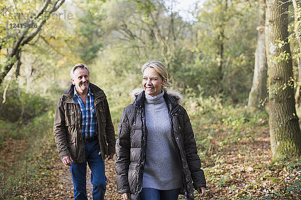 Lächelndes reifes Paar beim Spaziergang im sonnigen Herbstwald