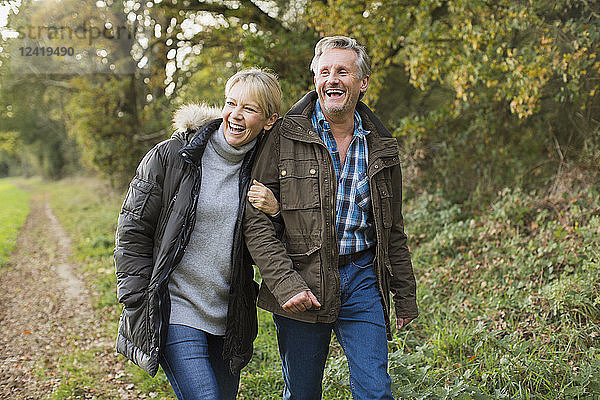 Glückliches  sorgloses reifes Paar  das Arm in Arm im Herbstpark spazieren geht