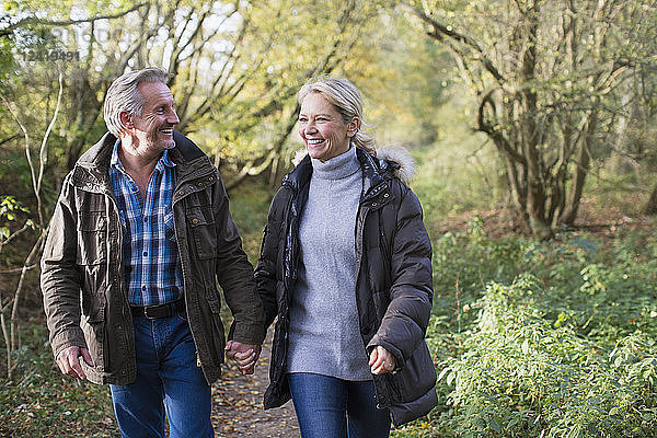 Glückliches  liebevolles reifes Paar  das sich an den Händen hält und im Herbstpark spazieren geht
