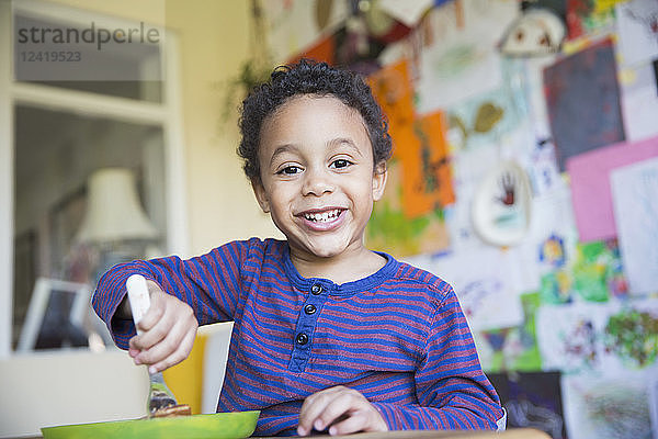 Porträt eines lächelnden  selbstbewussten Kleinkindes beim Essen
