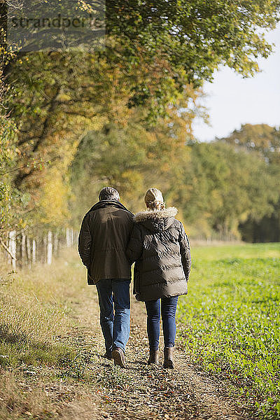 Zärtliches reifes Paar beim Spaziergang in einem sonnigen  ländlichen Herbstfeld
