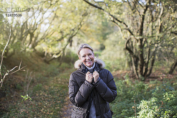 Porträt selbstbewusste reife Frau im Parka im sonnigen Herbstwald
