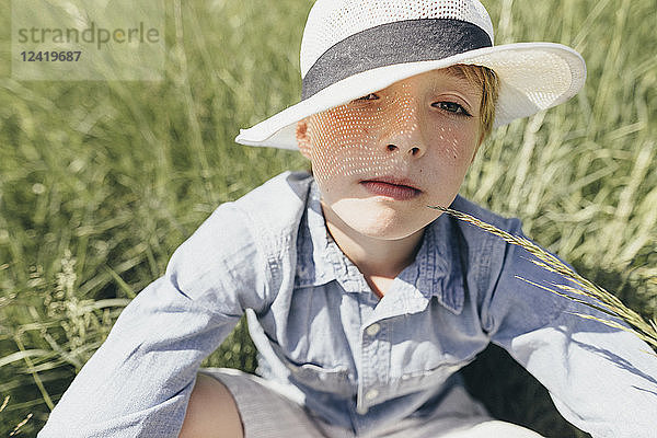 Portrait of boy wearing a hat sitting in field