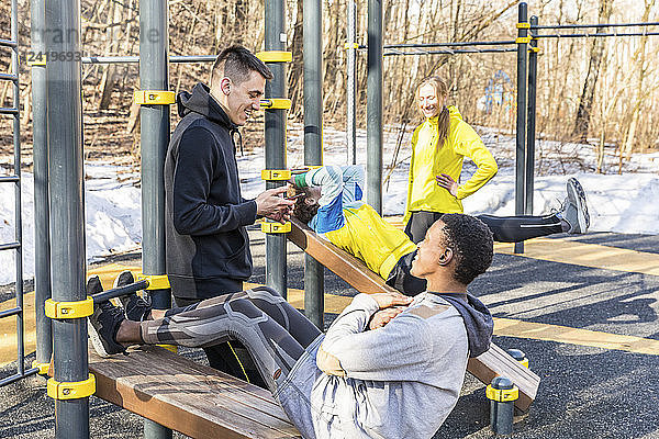 Friends exercising at fitness equipment in a park