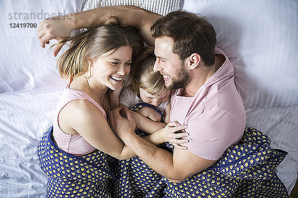 Happy family lying in bed  cuddling