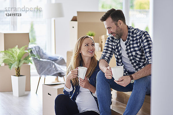 Man and pregnant woman moving into new flat having a coffee break