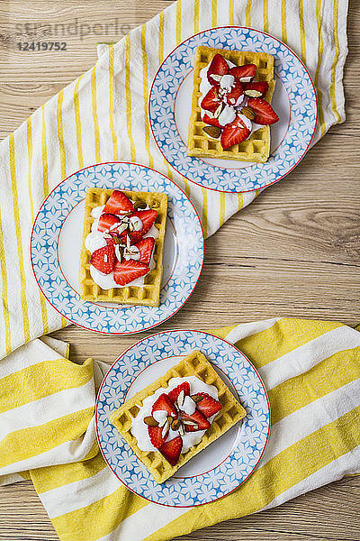 Three plates of waffles garnished with strawberries  Greek yogurt and almonds