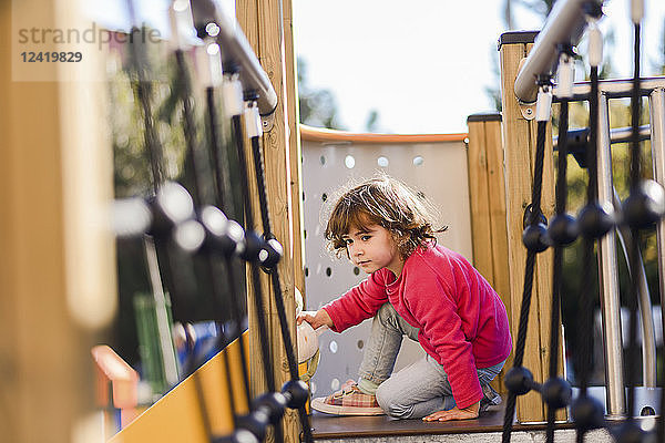 Portrait of little girl on climbing frame at playground