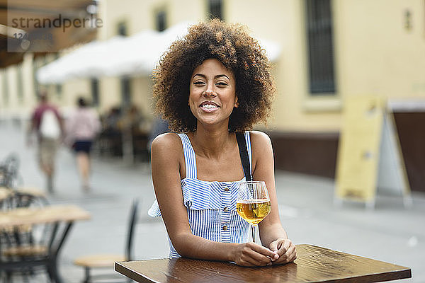 Portrait of happy young woman drinking beer outdoors