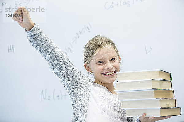 Portrait of happy schoolgirl carrying books in class