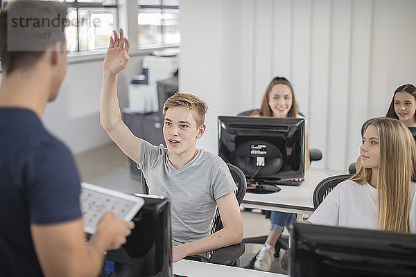 Boy raising hand in computer class