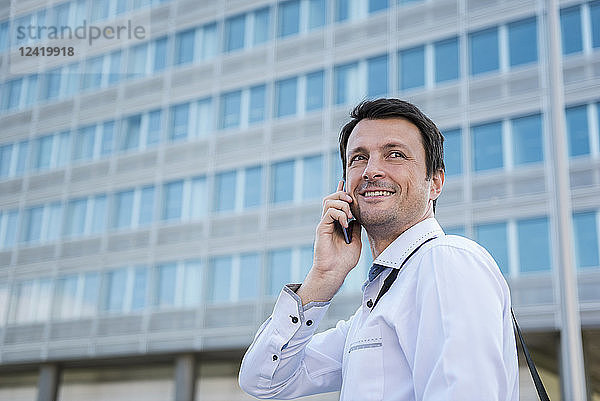 Smiling businessman on cell phone in the city