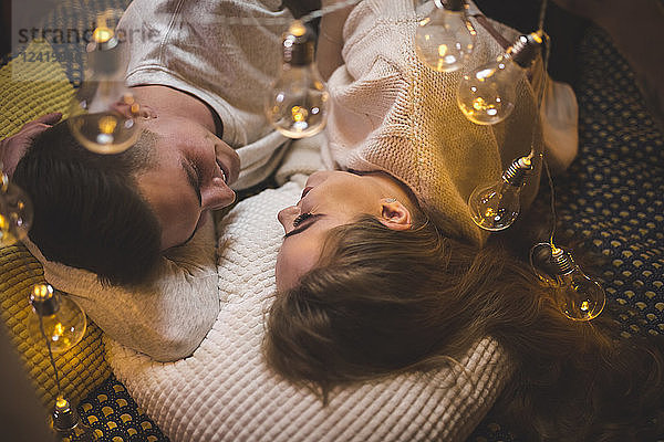 Romantic young couple cuddling in bed with fairy lights