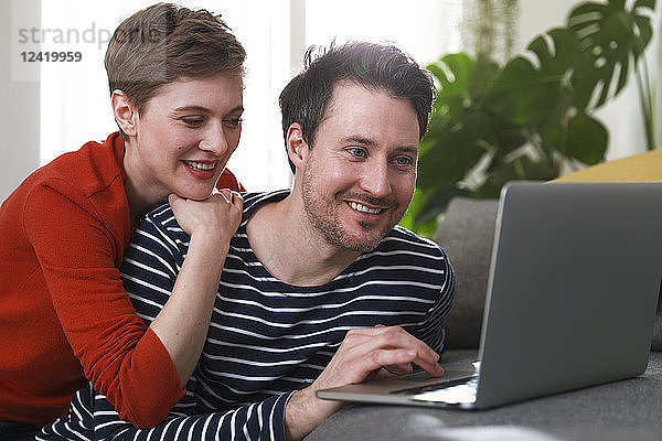 Couple sitting at home  using laptop